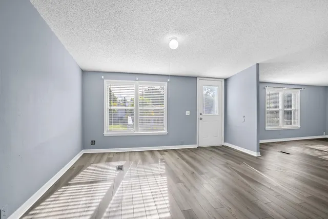 a view of an empty room with a window and wooden floor