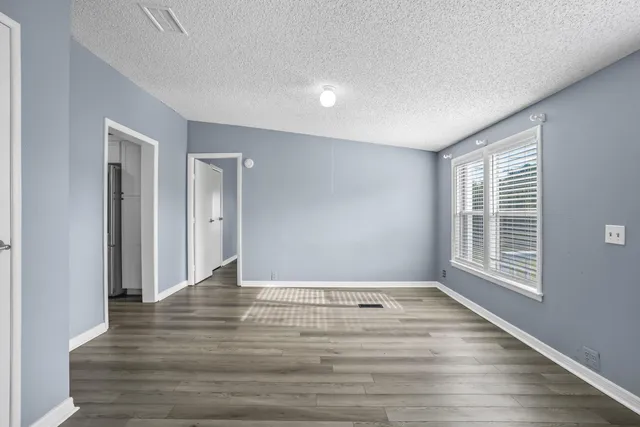 a view of an empty room with window and wooden floor