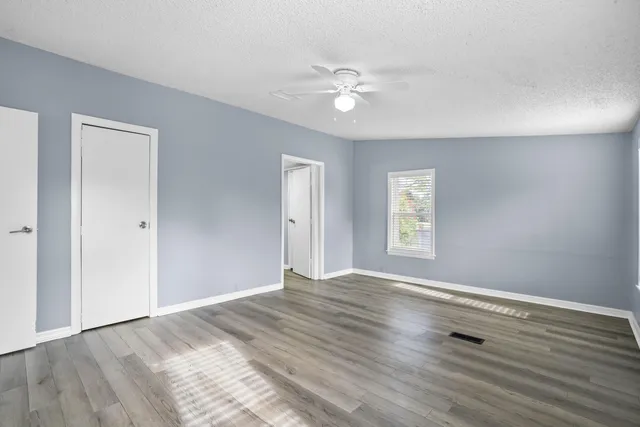 a view of empty room with wooden floor and fan