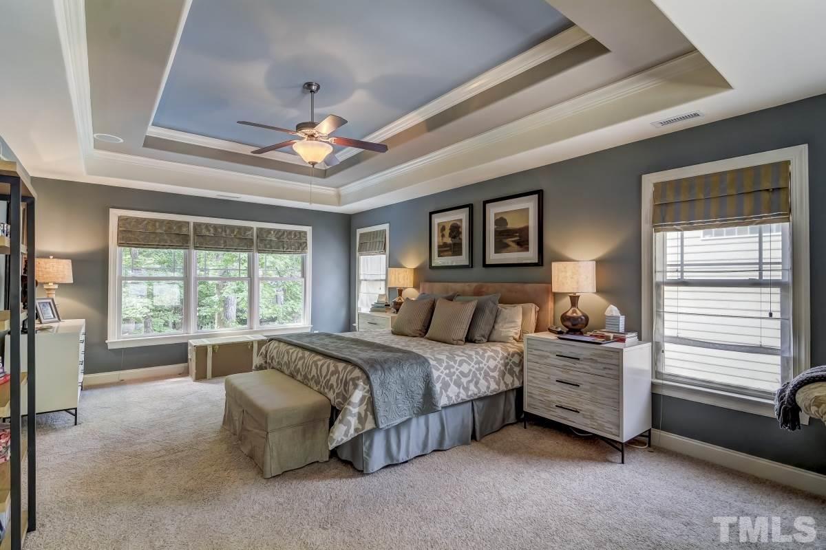 7207 Newport Avenue Raleigh, NC 27613 - Photo 12 of 25 a spacious bedroom with a bed a chandelier and a large window