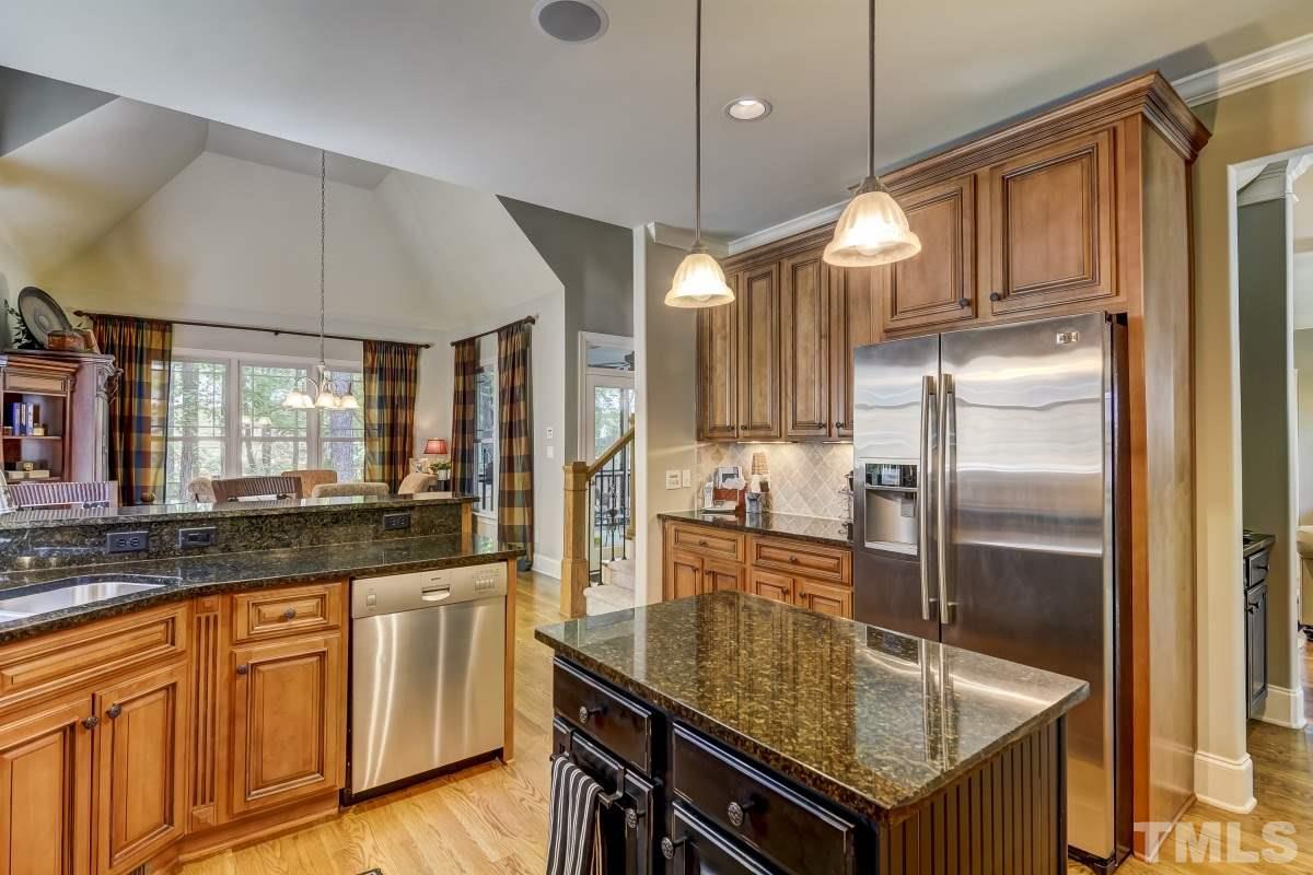 7207 Newport Avenue Raleigh, NC 27613 - Photo 9 of 25 a kitchen with kitchen island granite countertop a sink a counter space appliances and cabinets