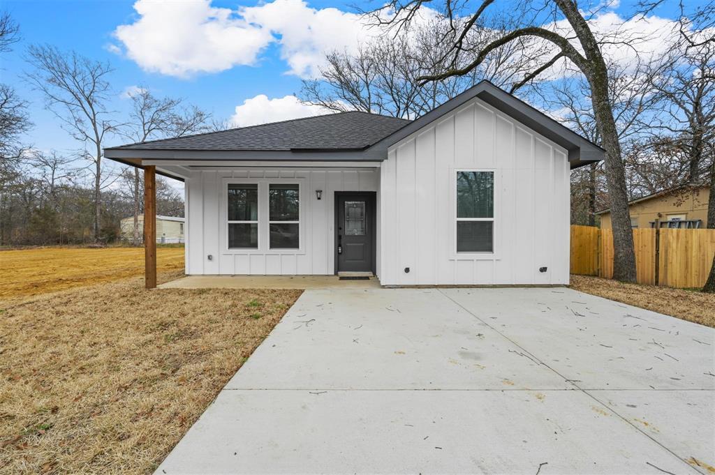 View of front of home featuring board and batten siding, roof with shingles, concrete driveway, and covered porch