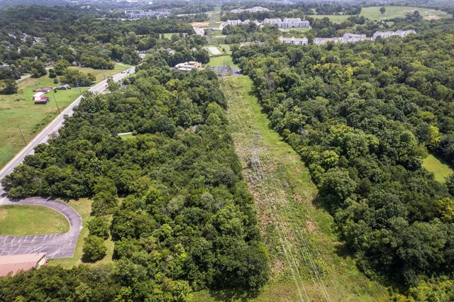 an aerial view of residential house with outdoor space and trees all around