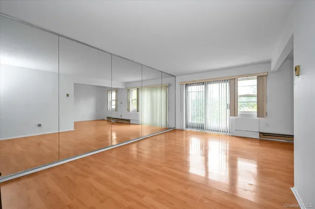 a view of an empty room with window and wooden floor