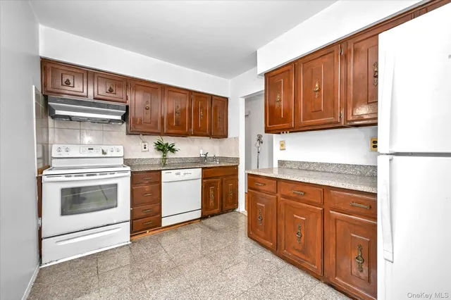 a kitchen with granite countertop wooden cabinets and white appliances
