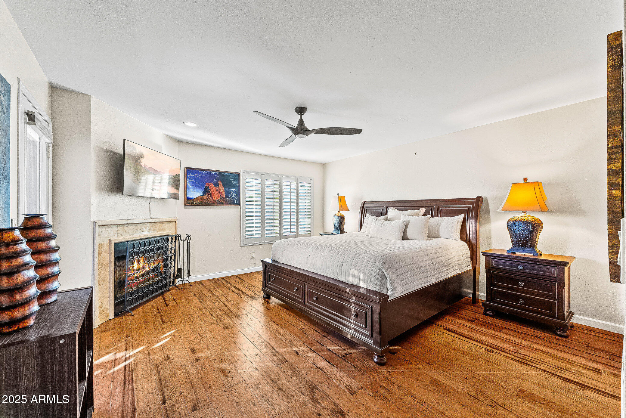 6159 East Indian School Road, Unit 104 Scottsdale, AZ 85251 - Photo 14 of 24 a bedroom with a bed dresser and a fireplace