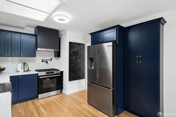 a kitchen with stainless steel appliances a refrigerator stove and wooden floor