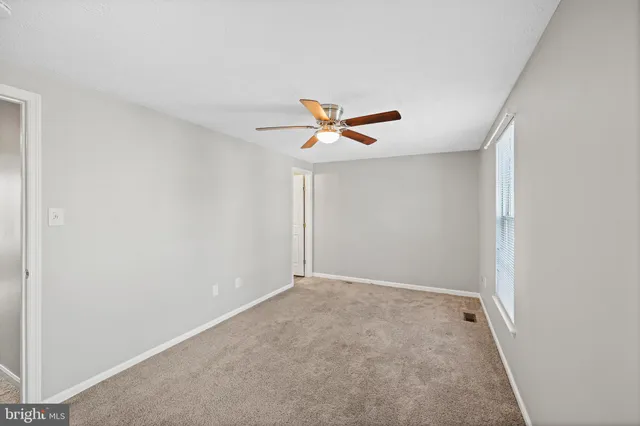 an empty room with a ceiling fan and wooden floor