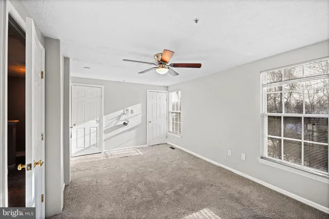 a view of an empty room with a ceiling fan and window