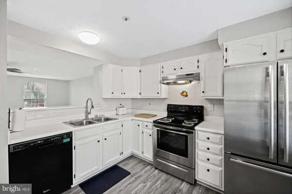 a kitchen with a refrigerator sink and white cabinets