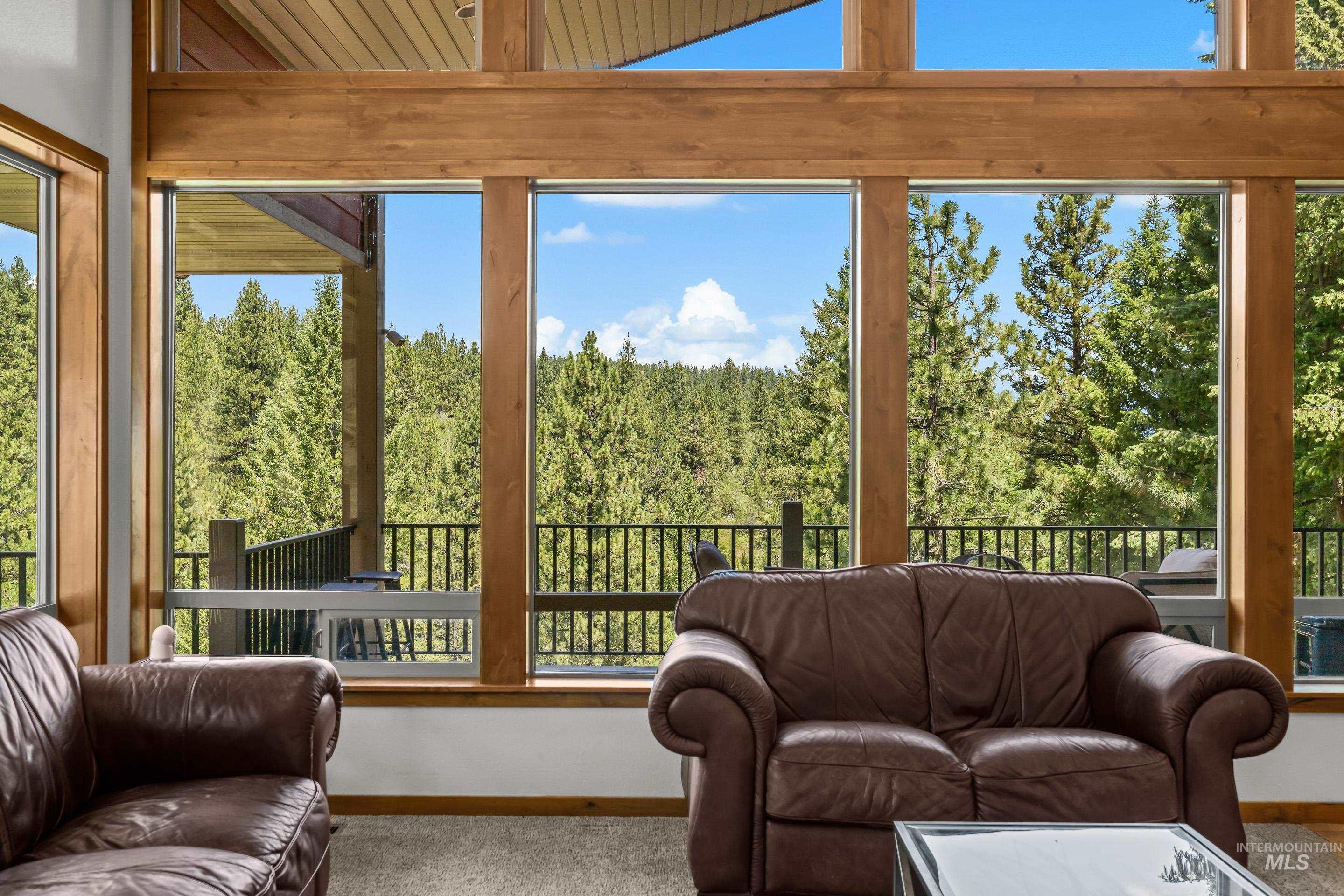 92 Cruickshank Road Horseshoe Bend, ID 83629 - Photo 8 of 50 Expansive window wall with natural wood framing, showcasing abundant natural light and evergreen tree scenery
