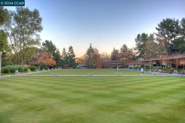 a front view of a building with a garden and trees