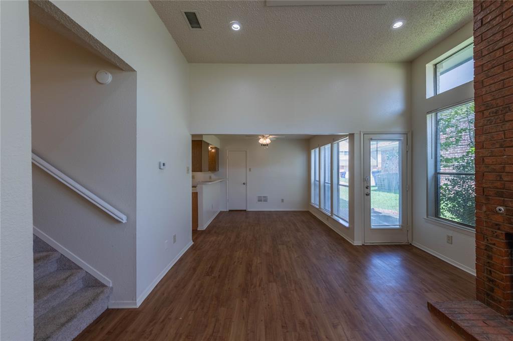 7551 Tournament Road Frisco, TX 75035 - Photo 1 of 1 Unfurnished living room featuring dark wood finished floors, a textured ceiling, ceiling fan, stairway, and a high ceiling