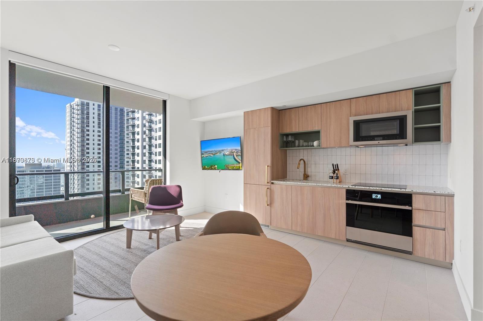 159 Northeast 6th Street, Unit 2403 Miami, FL 33132 - Photo 9 of 18 a kitchen with a table chairs microwave and cabinets