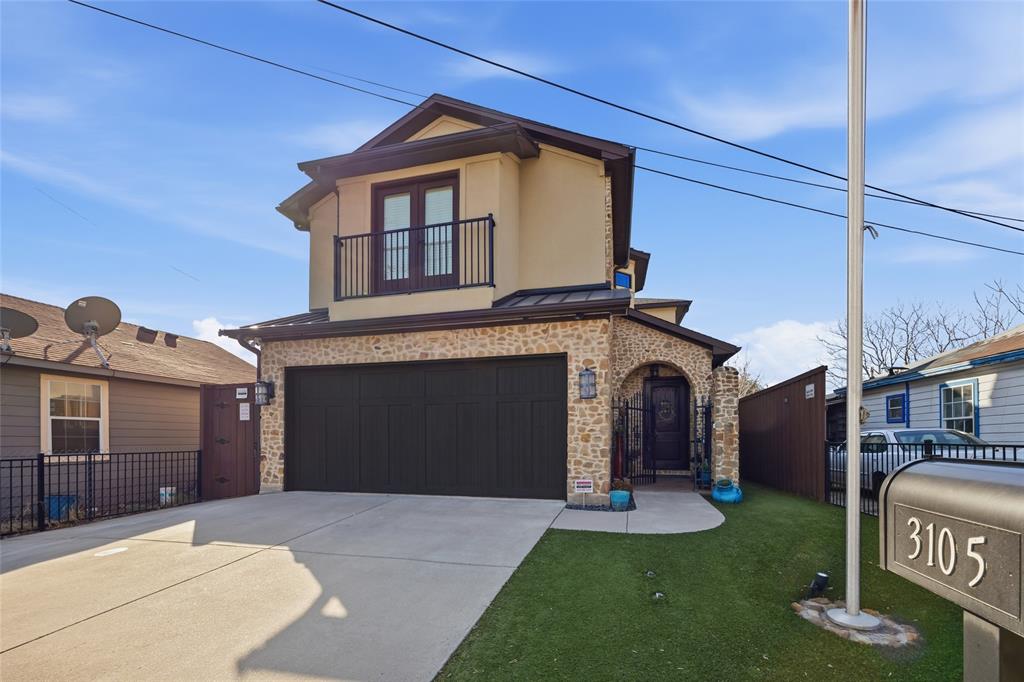 3105 Pastor Street Dallas, TX 75212 - Photo 27 of 28 View of front of home featuring a balcony, an attached garage, concrete driveway, and stone siding plus durable turf for easy maintenance