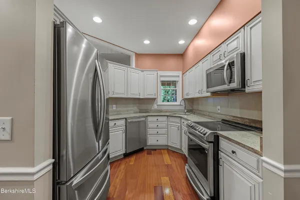 a kitchen with stainless steel appliances granite countertop a refrigerator a stove top oven and sink