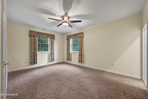 a view of a big room with windows and chandelier fan