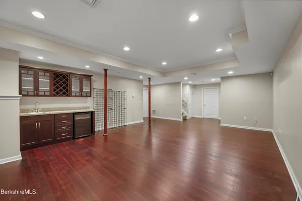 a view of an empty room with wooden floor and kitchen