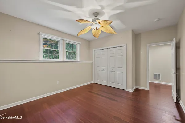 an empty room with wooden floor closet and windows