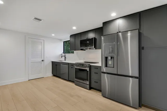 a large kitchen with stainless steel appliances a refrigerator and a stove