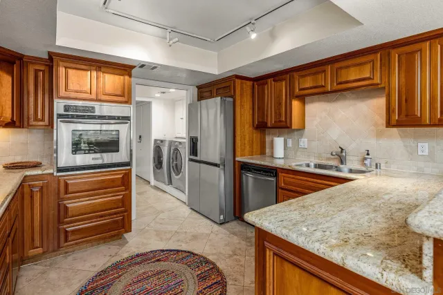 a kitchen with stainless steel appliances granite countertop sink stove and refrigerator
