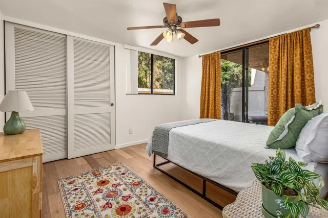 a bedroom with a bed window and walk in closet with wooden floor