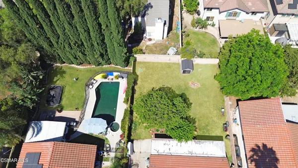 an aerial view of a house with outdoor space and trees all around