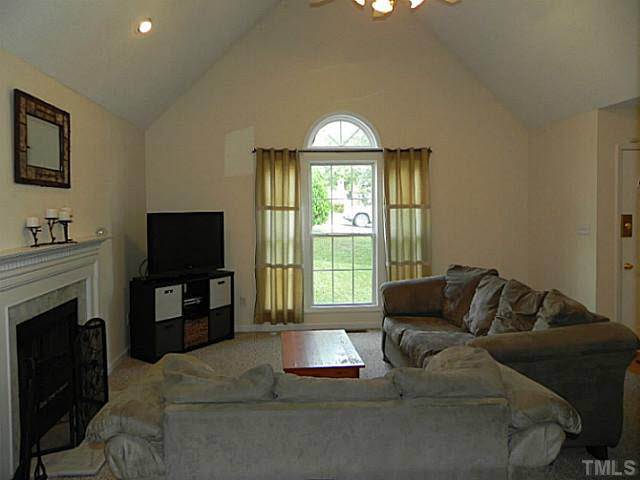 4517 Whistling Way Raleigh, NC 27616 - Photo 7 of 24 a living room with furniture a fireplace and a flat screen tv
