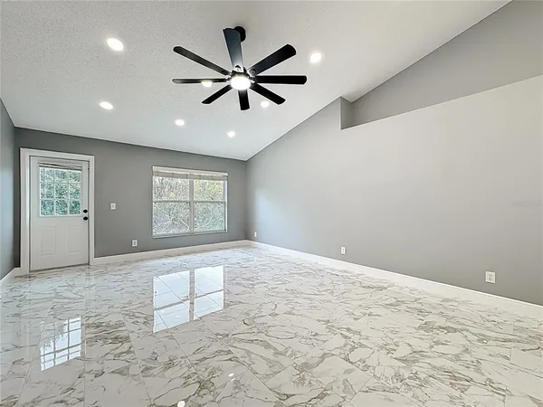 an empty room with wooden floor and ceiling fan