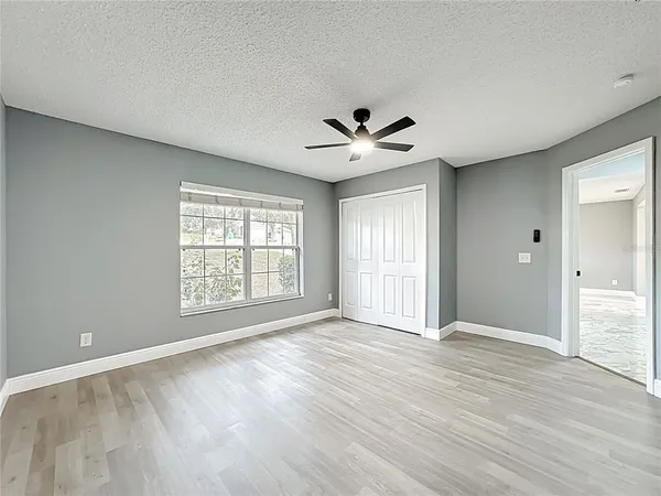 a view of an empty room with a window and wooden floor