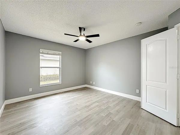 an empty room with wooden floor ceiling fan and windows