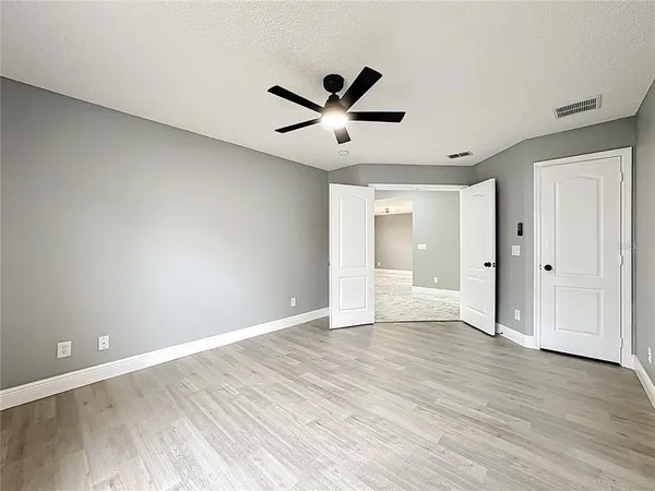an empty room with wooden floor and ceiling fan