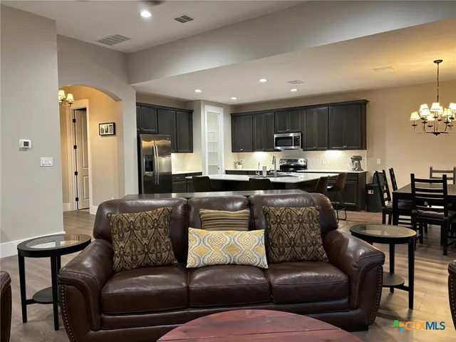 a living room with stainless steel appliances kitchen island granite countertop furniture a rug and a view of kitchen