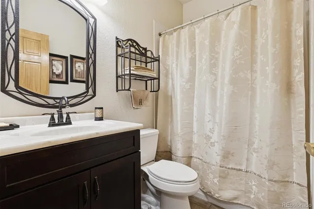 a bathroom with a granite countertop sink toilet and mirror