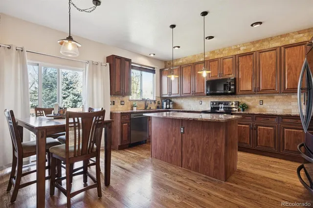 a kitchen with stainless steel appliances granite countertop wooden floors a stove a microwave a center island and a window