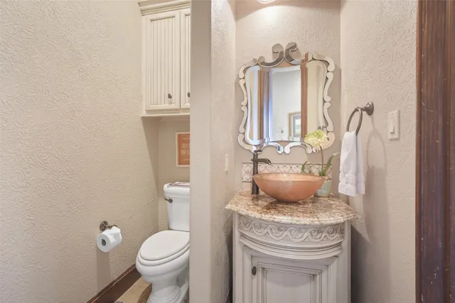 a bathroom with a granite countertop toilet sink and mirror