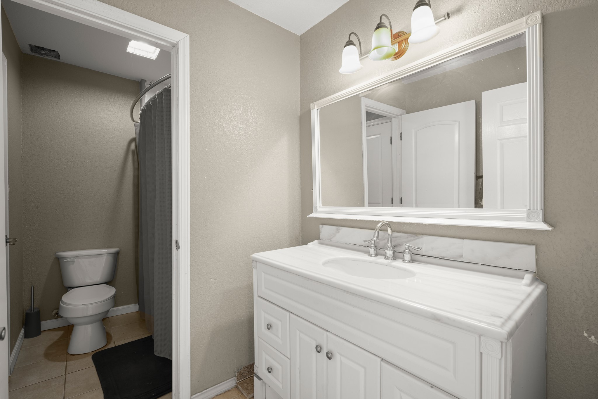 9725 Bock Road Buda, TX 78610 - Photo 14 of 32 A well-appointed bathroom with a marble-topped vanity and an adjacent private commode area.