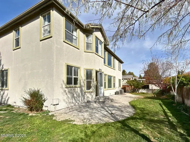 a view of a yard in front of a brick house with a large tree