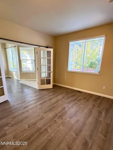 an empty room with wooden floor and windows