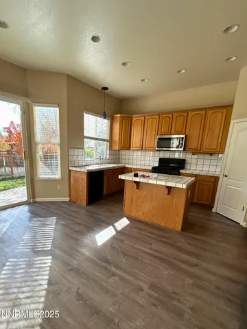 a large kitchen with stainless steel appliances wooden floors and wooden cabinets