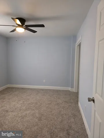 an empty room with a chandelier fan and windows