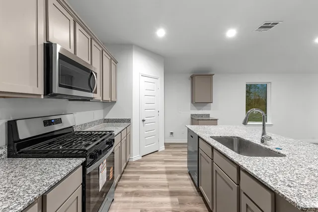 a kitchen with stainless steel appliances granite countertop a sink stove microwave and cabinets