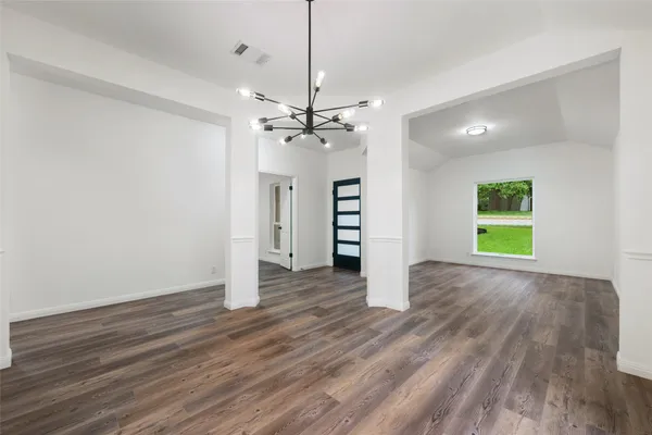 a view of an empty room with wooden floor and window