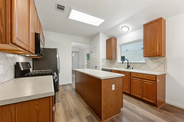 a kitchen with stainless steel appliances granite countertop a sink stove microwave and refrigerator