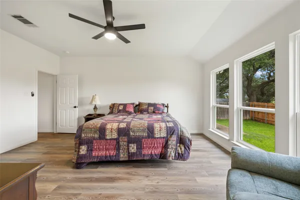 an empty room with wooden floor ceiling fan and windows