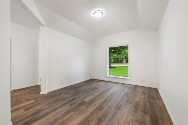 a view of a room with wooden floor ceiling fan and windows