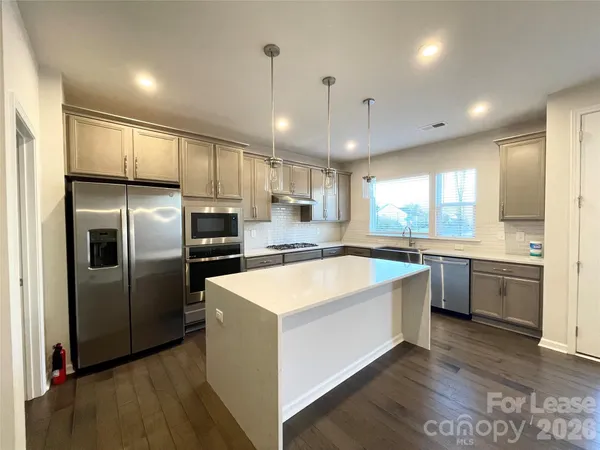 a large kitchen with kitchen island a large counter top stainless steel appliances and cabinets