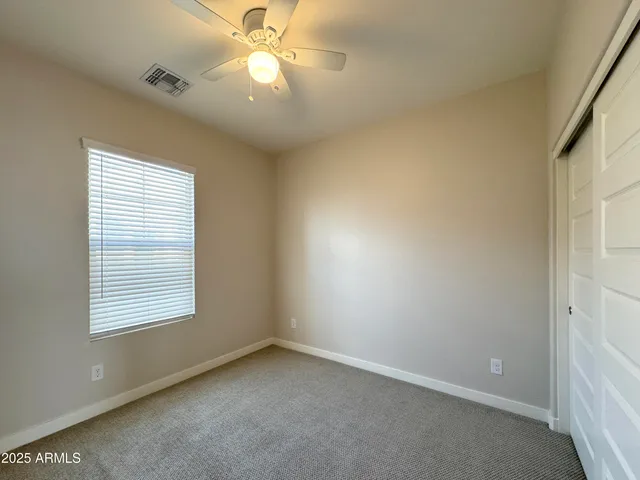 an empty room with a window and a fan