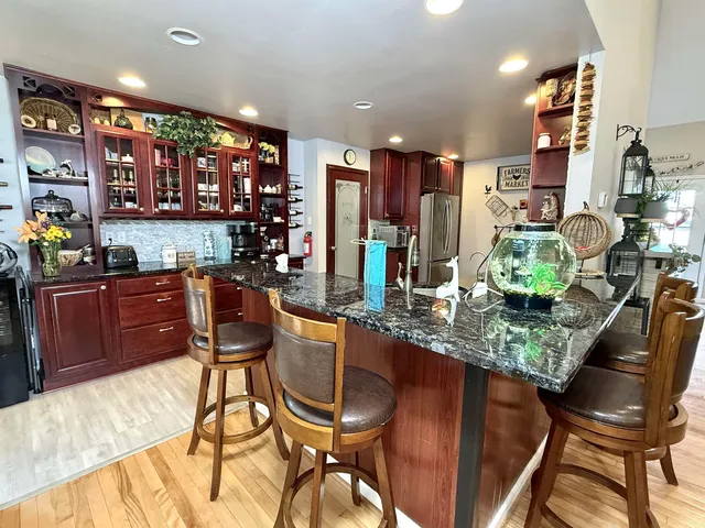 a kitchen with stainless steel appliances granite countertop a stove top oven a sink dishwasher and wooden cabinets with wooden floor
