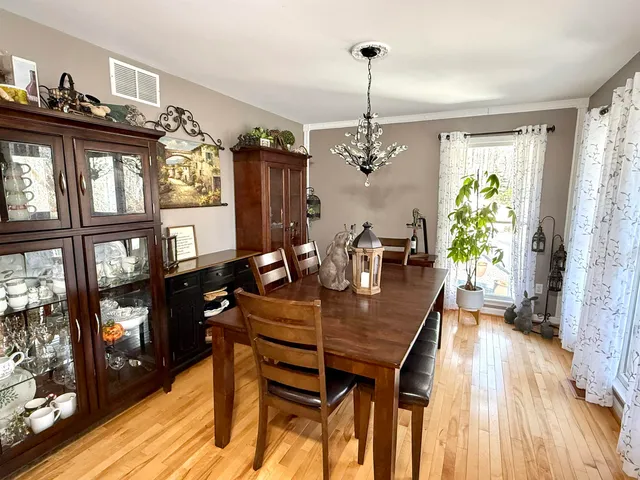 a dining room with wooden floor a chandelier a wooden table and chairs